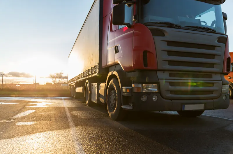 Een scraper die elke week 26.000 Google resultaten verzamelt over Truck Theft Rode vrachtwagen met oplegger geparkeerd op een terrein bij zonsondergang